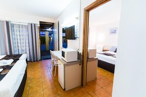 A hotel room with a bed, a desk with a microwave, a small refrigerator, and a television on the wall. - Gladstone Motel (South Gladstone)