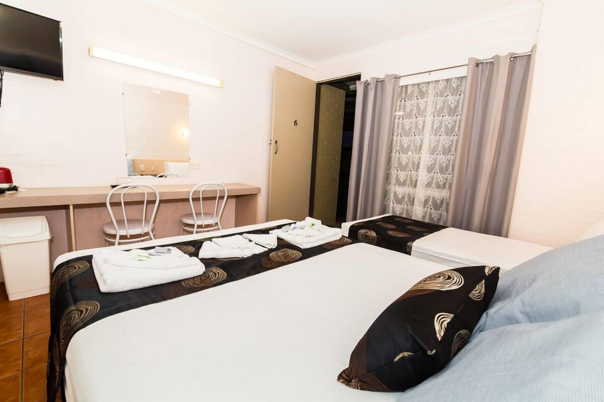 A hotel room with a bed, a desk, a chair, a TV, and a bathroom.