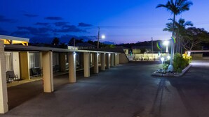 Et motel med flere værelser, et overdækket udendørs siddeområde og en parkeringsplads.