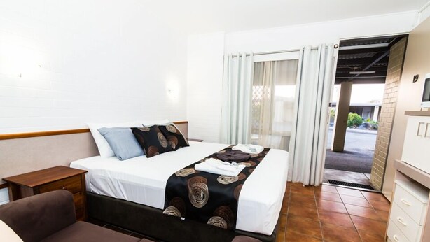 Et hotelværelse med en seng, en sofa, et lille bord og et tekøkken.
