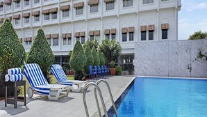 A swimming pool with lounge chairs and a building with multiple windows in the background. - Mystical Valley View Resort and Spa, Udaipur (Udaipur)