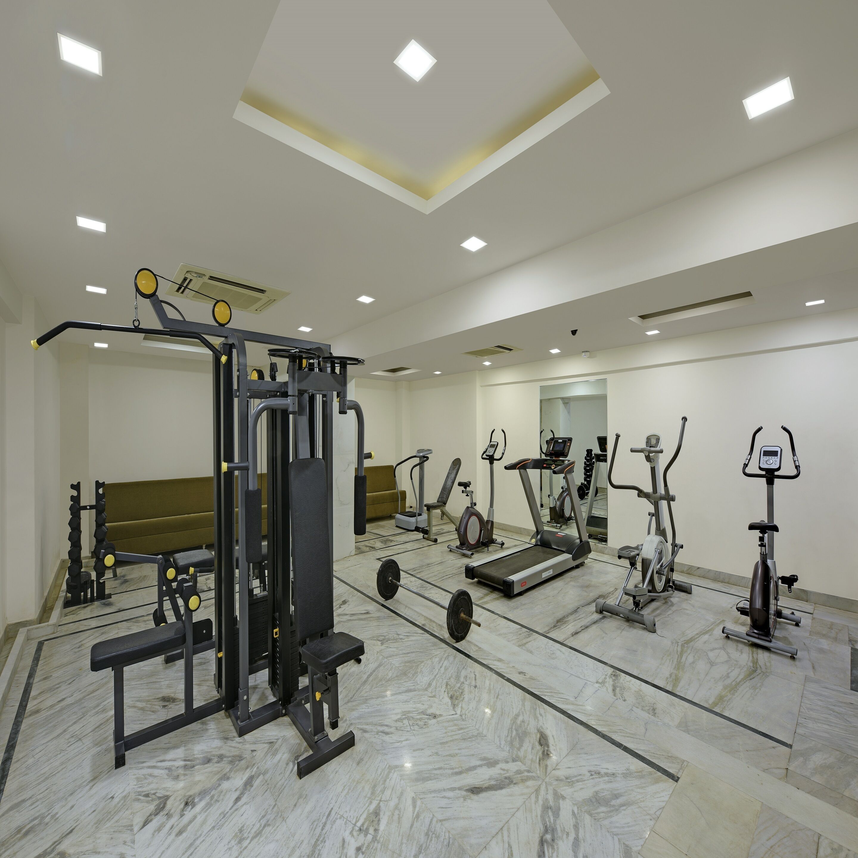Un gimnasio con diverso equipo de ejercicio, una banca y un espejo grande.