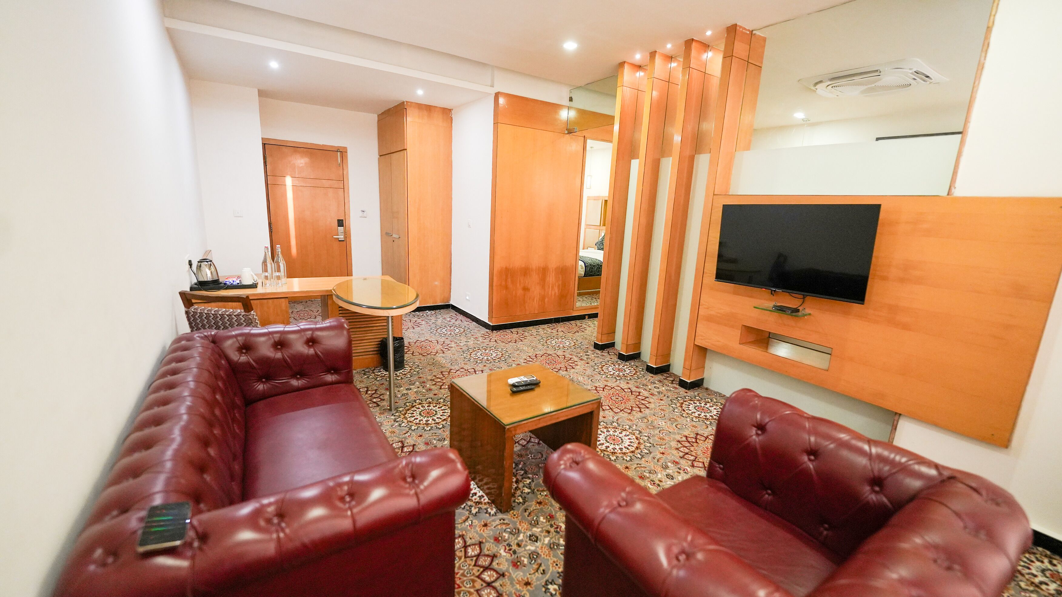 Una habitación de hotel con sofá, televisor, una mesita y alfombra estampada.