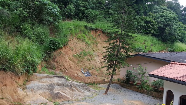 A residential area with a house, a small garden, and a sloped terrain with a drainage ditch. - Lodge in 611 (Kandy)