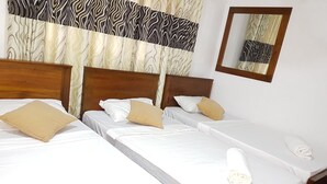 A hotel room with two beds, each with white linens and beige pillows. There is a wooden headboard, a mirror on the wall, and a patterned curtain. - Lodge in 611 (Kandy)