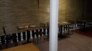 A restaurant with wooden tables and chairs, a white column, and bamboo wall panels. - Lodge in 611 (Kandy)