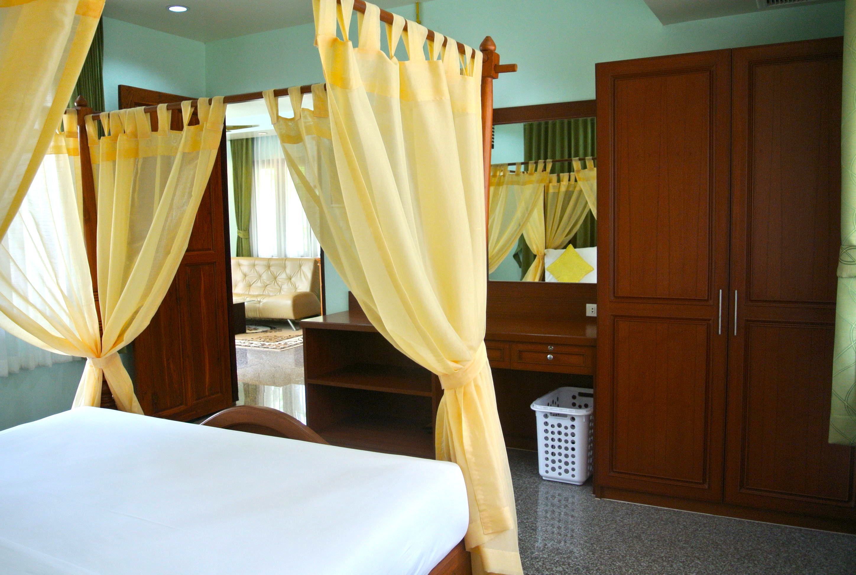 A bedroom with a bed, wooden wardrobe, and a mirror.