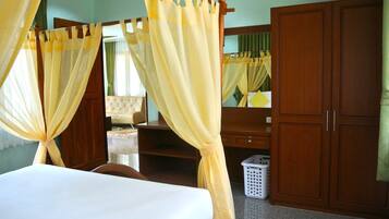 A bedroom with a bed, wooden wardrobe, and a mirror.