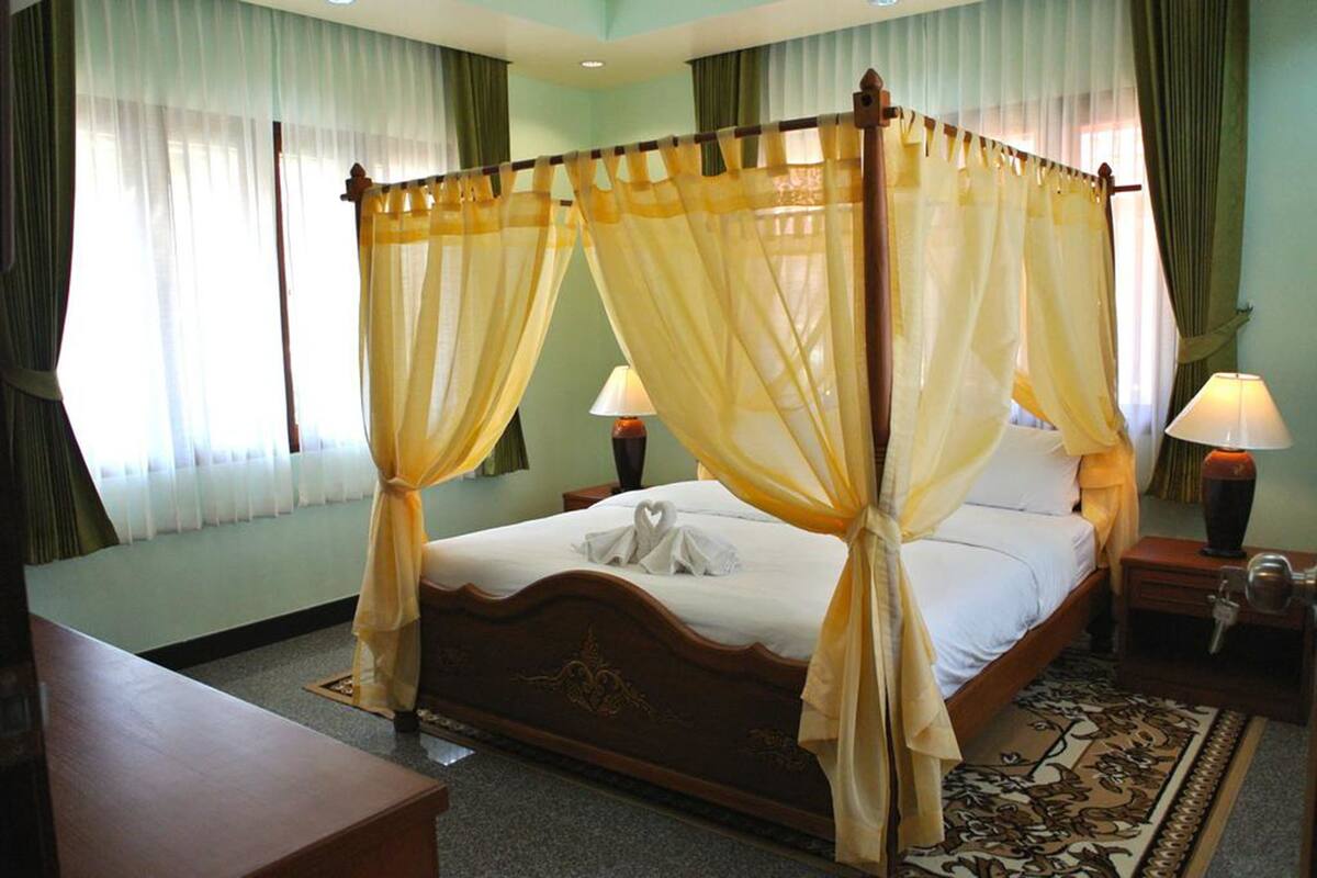 A four-poster bed with a canopy, two bedside tables with lamps, a wooden headboard, and a patterned rug.