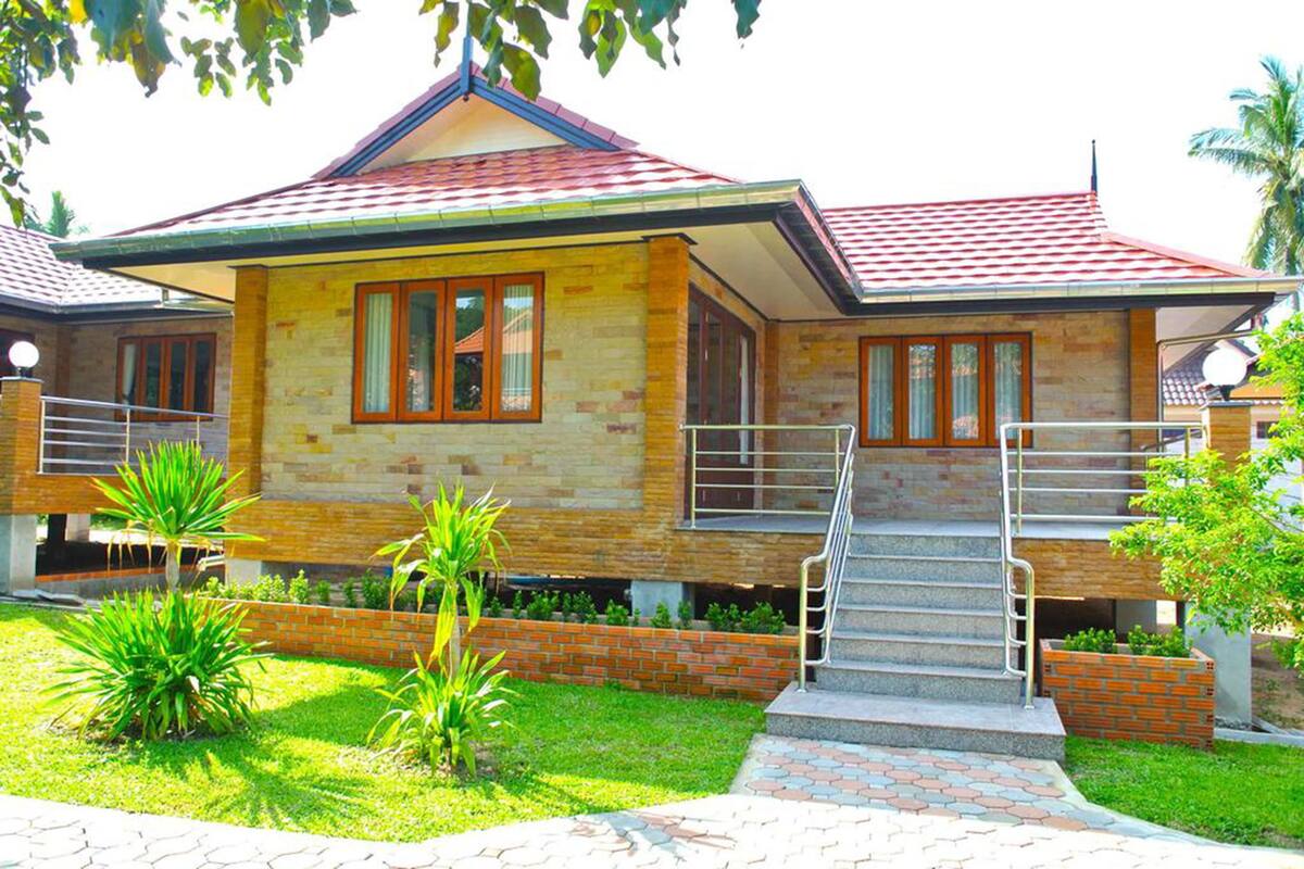 A two-story house with a red-tiled roof, a brick exterior, and a small front garden.