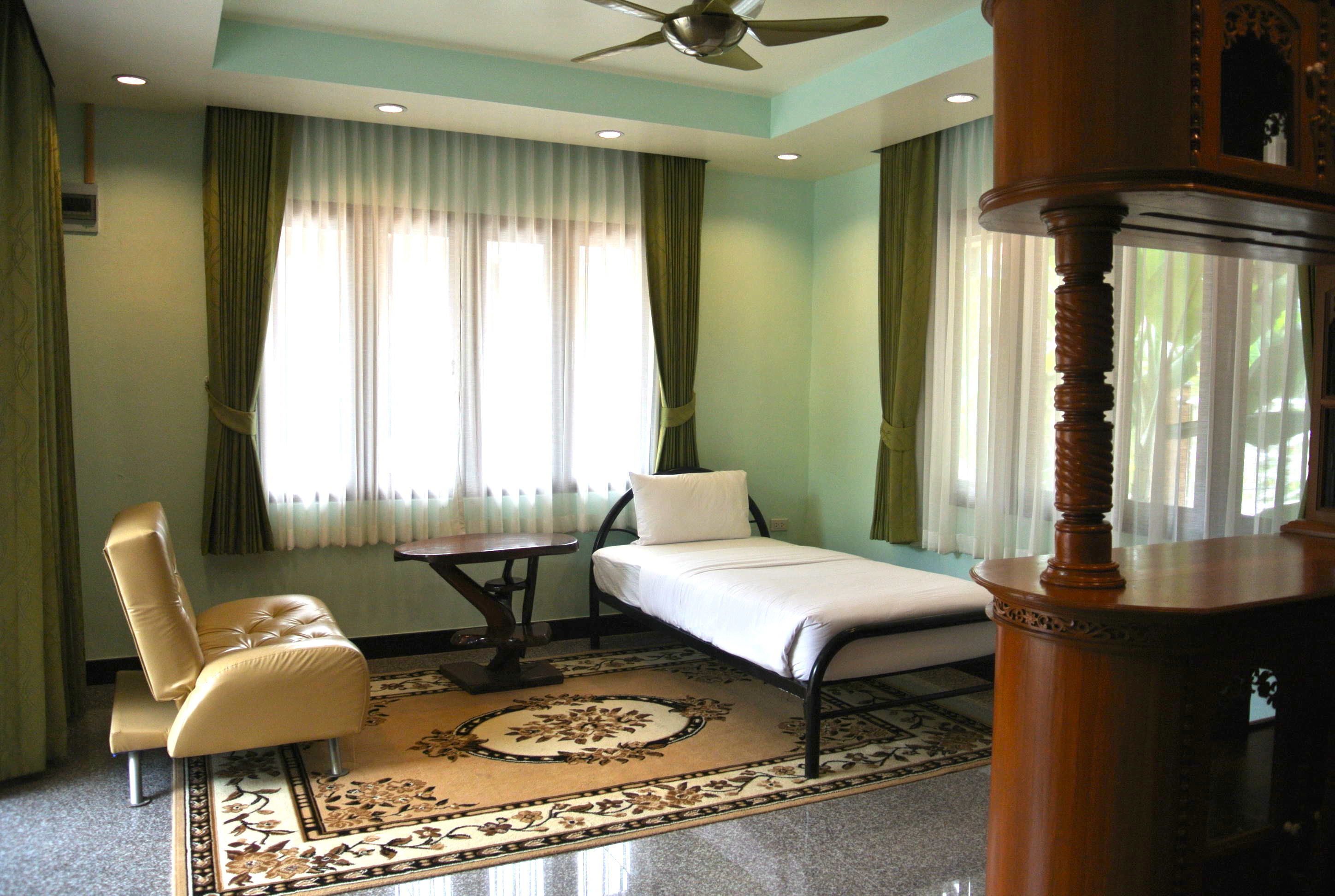 A bedroom with a bed, a chair, a small table, and a ceiling fan.