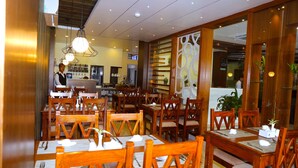 A restaurant with wooden tables and chairs, a bar area, and a counter.