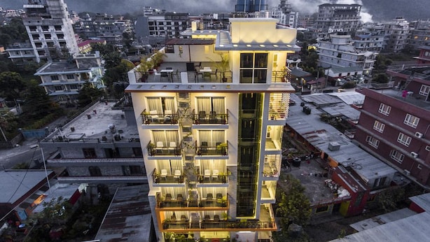 A multi-story hotel with balconies, a central staircase, and a view of the surrounding urban area.