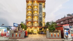 A multi-story hotel with a central entrance, balconies, and a visible laundry service sign.