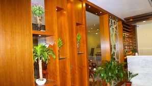 A wooden reception desk with potted plants and a glass partition.
