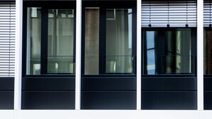 Un edificio moderno con entrada de vidrio, plantas en macetas y un letrero que dice Eric Vokel.