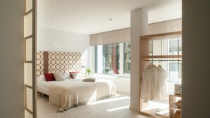 Un dormitorio moderno con una cama grande, un armario y una ventana con vistas a la ciudad.