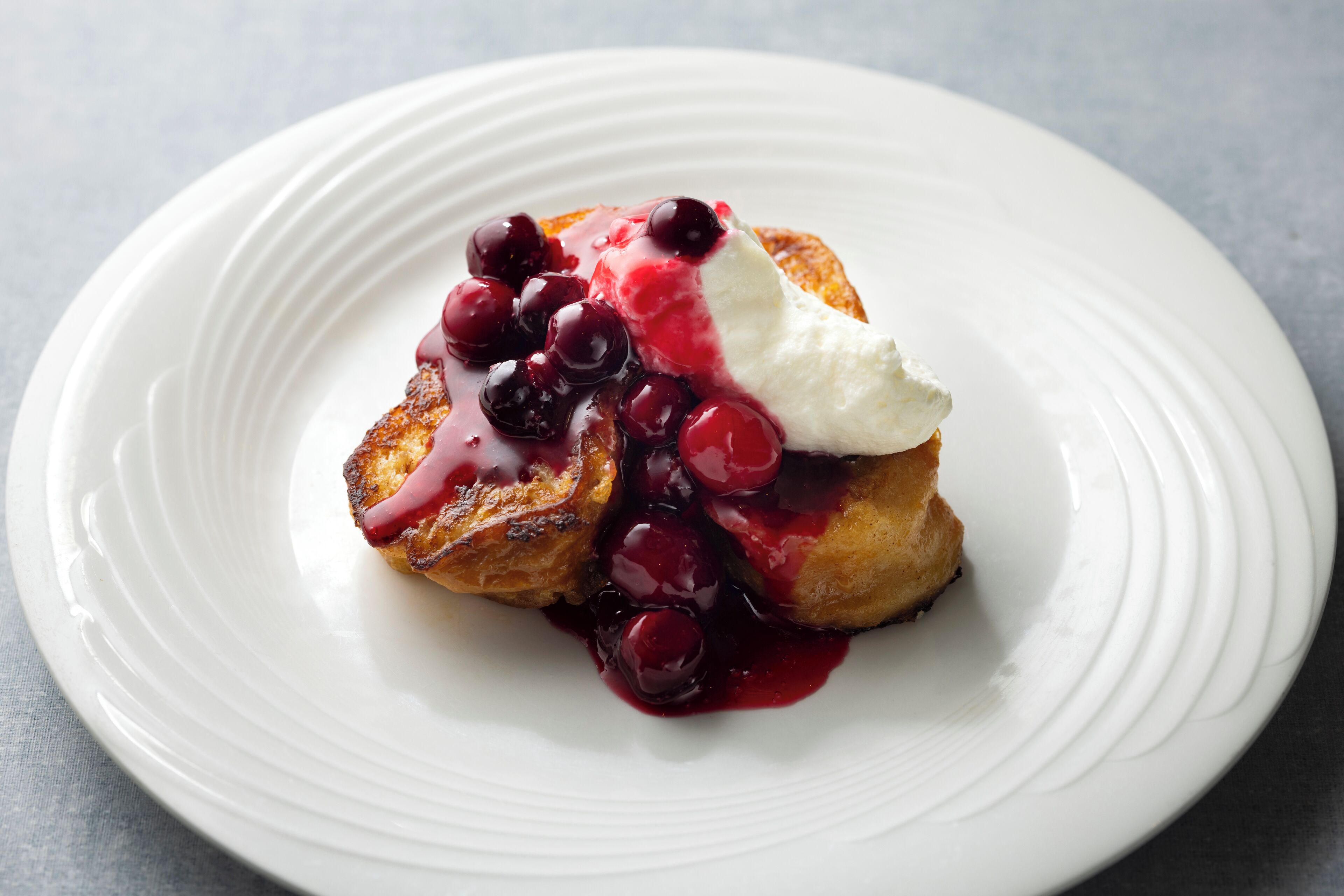 Dessert på hvid tallerken med bærkompot og flødeskum.