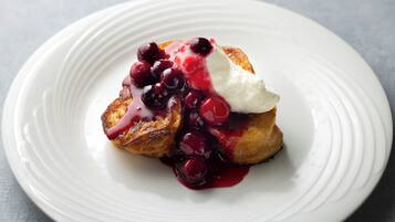 Dessert på hvid tallerken med bærkompot og flødeskum.