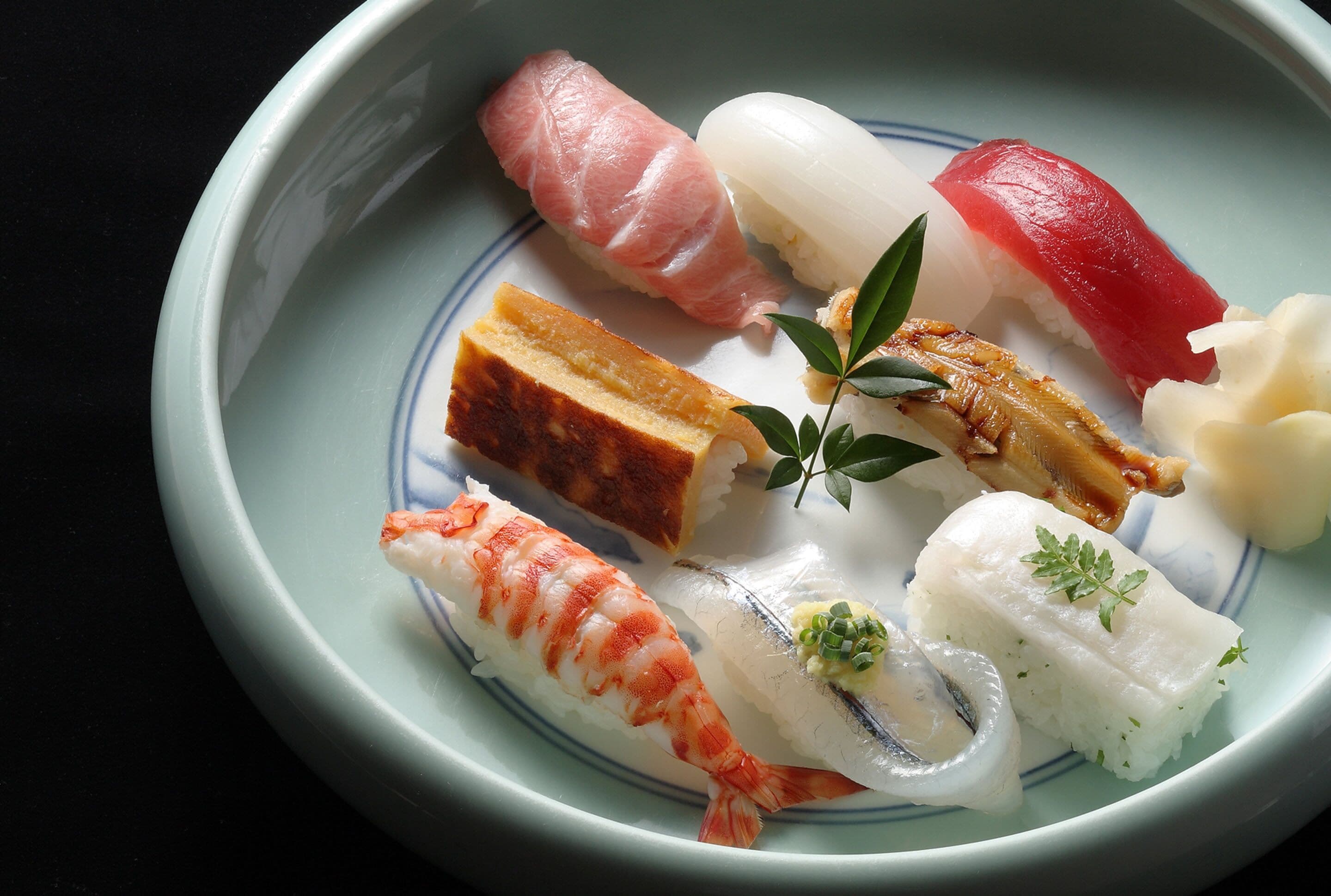 Een bord met verschillende soorten sushi en een kleine garnering.