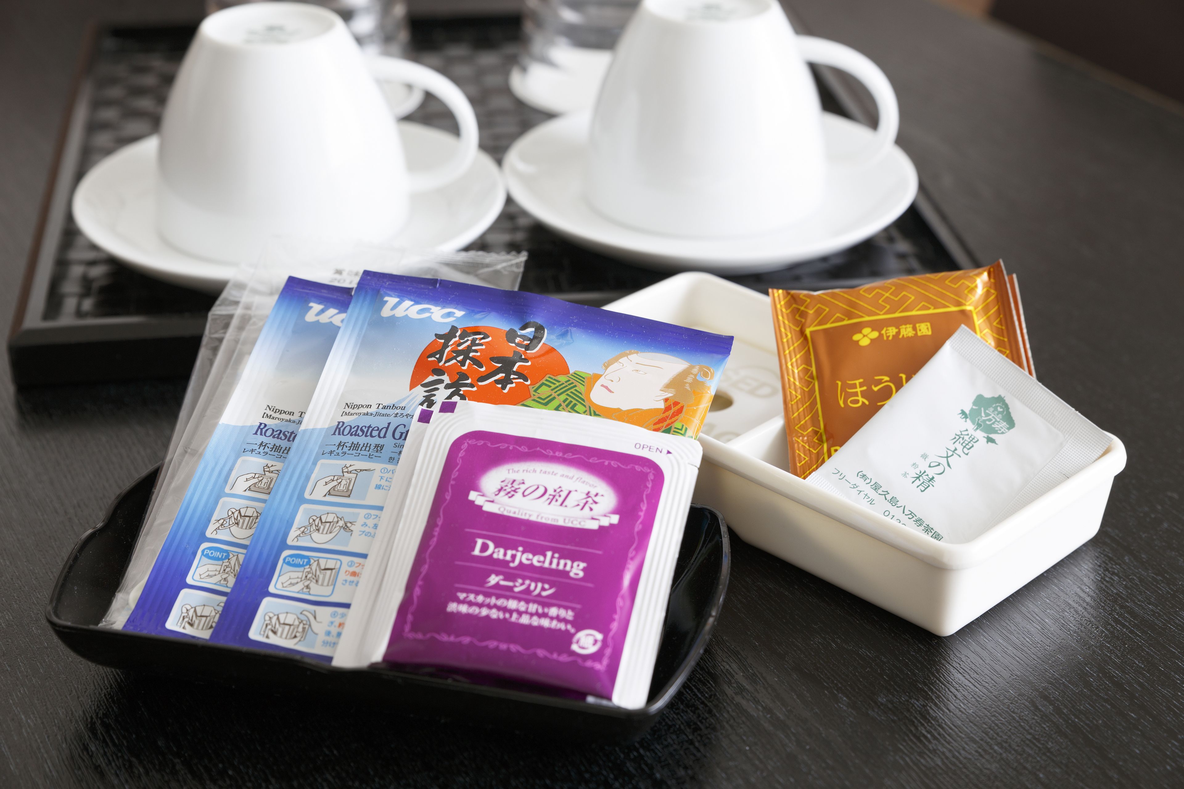 A tray with tea packets and white cups on a table.