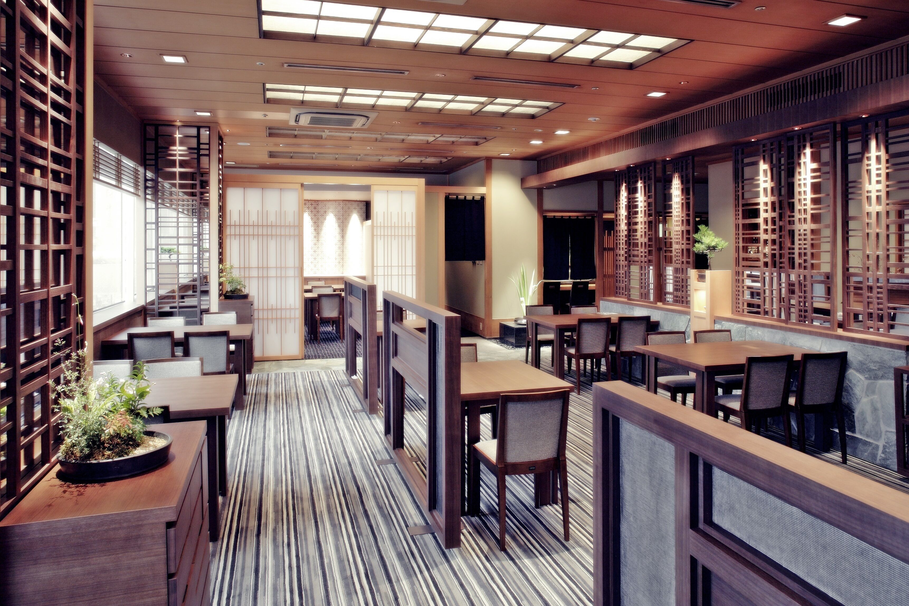 Un restaurante moderno con paneles de madera, suelo a rayas y varias zonas de comedor.