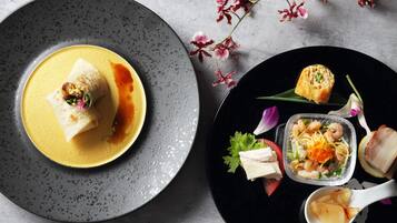 A dining table with a variety of dishes, including a plate with a rolled item and a bowl with a seafood dish.