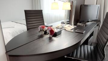 Une chambre d’hôtel avec un lit, un bureau doté d’une lampe, une télévision et une chaise.