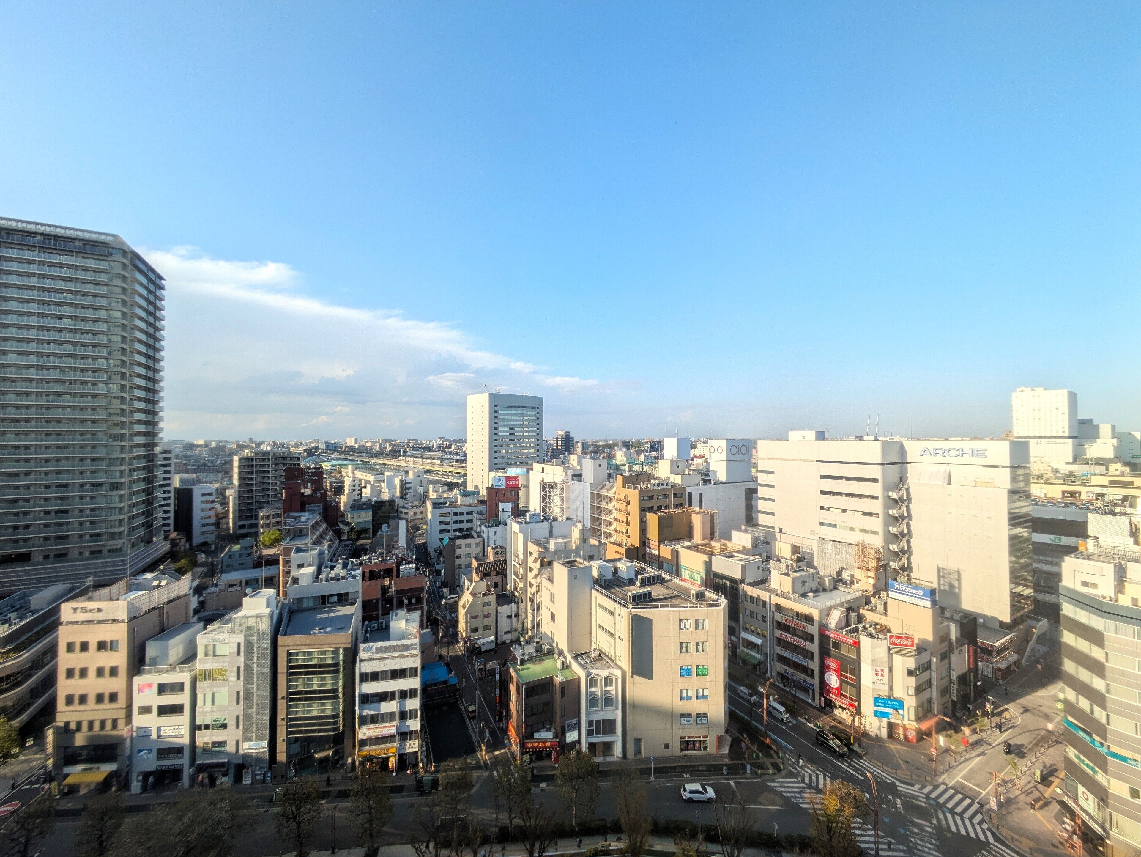 A cityscape with various buildings, including a prominent white building with "ARCH" on it, and a large curved building on the left.