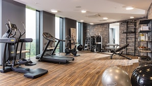 A gym with treadmills, elliptical machines, free weights, and exercise balls.