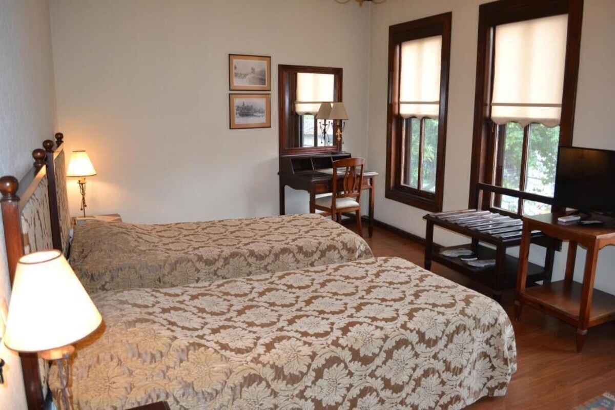 A room with two beds, a desk, a chair, and a television.