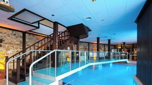 Ein großer, überdachter Pool mit Glasgeländern und einer Wand aus Stein im Hintergrund.