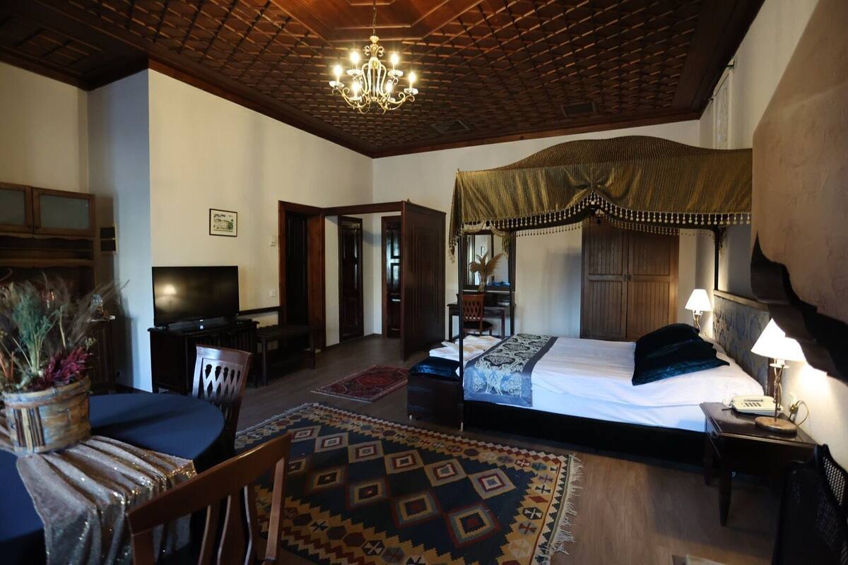 A bedroom with a canopy bed, a television, a desk, and a chair.