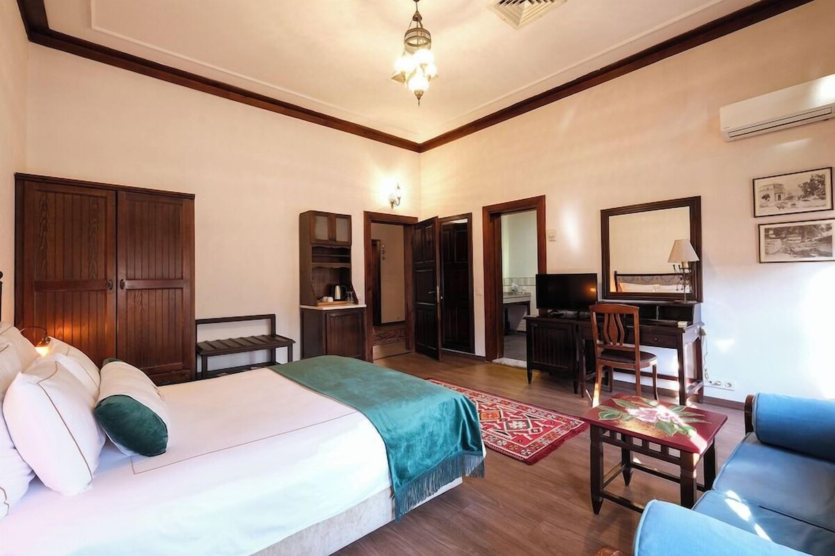 A bedroom with a bed, a desk, a chair, a TV, and a wardrobe.