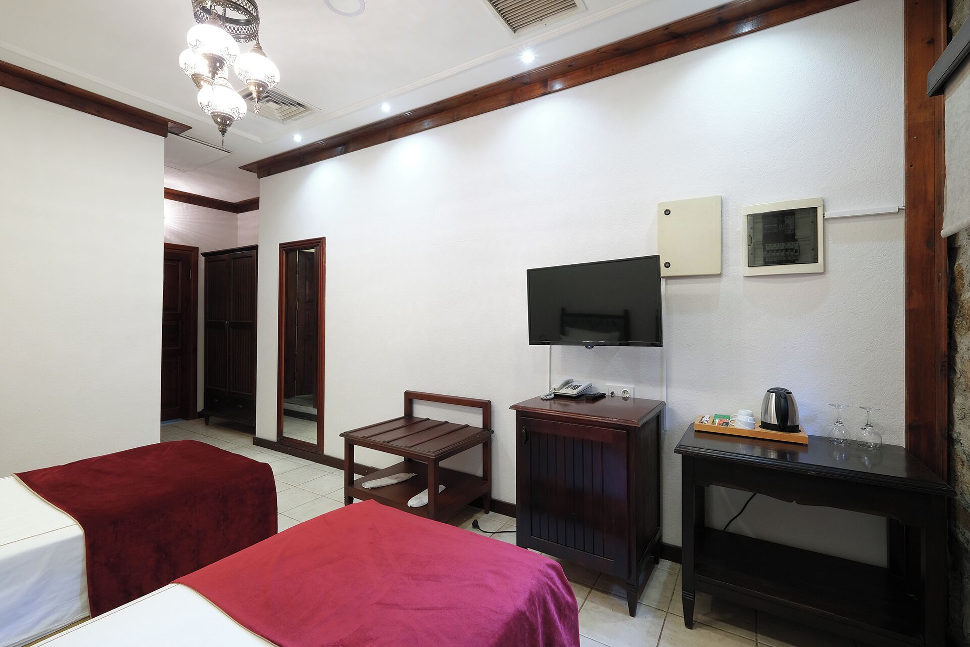 A hotel room with two beds, a desk, a television, and a coffee maker.