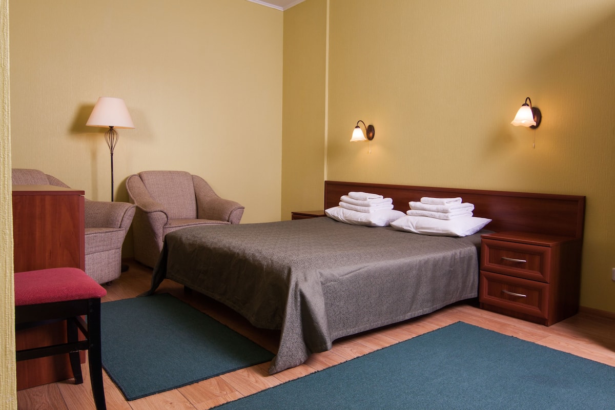 Una habitación de hotel con cama, una silla, un escritorio y una lámpara.