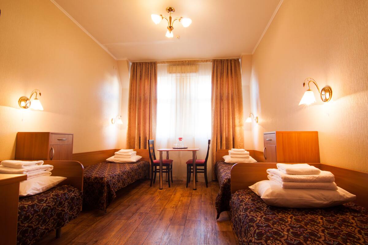 Una habitación de hotel con dos camas individuales, una mesita, sillas y un escritorio.