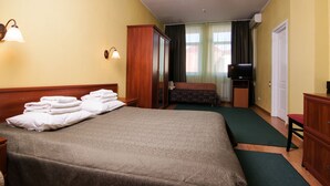 Hotellihuone, jossa on suuri sänky, työpöytä, televisio ja vaatekaappi.