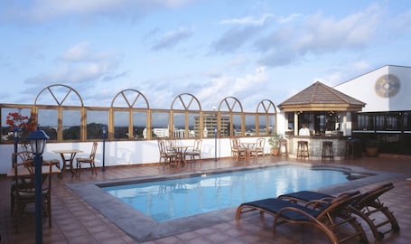 Una piscina al aire libre, sillones reclinables de piscina