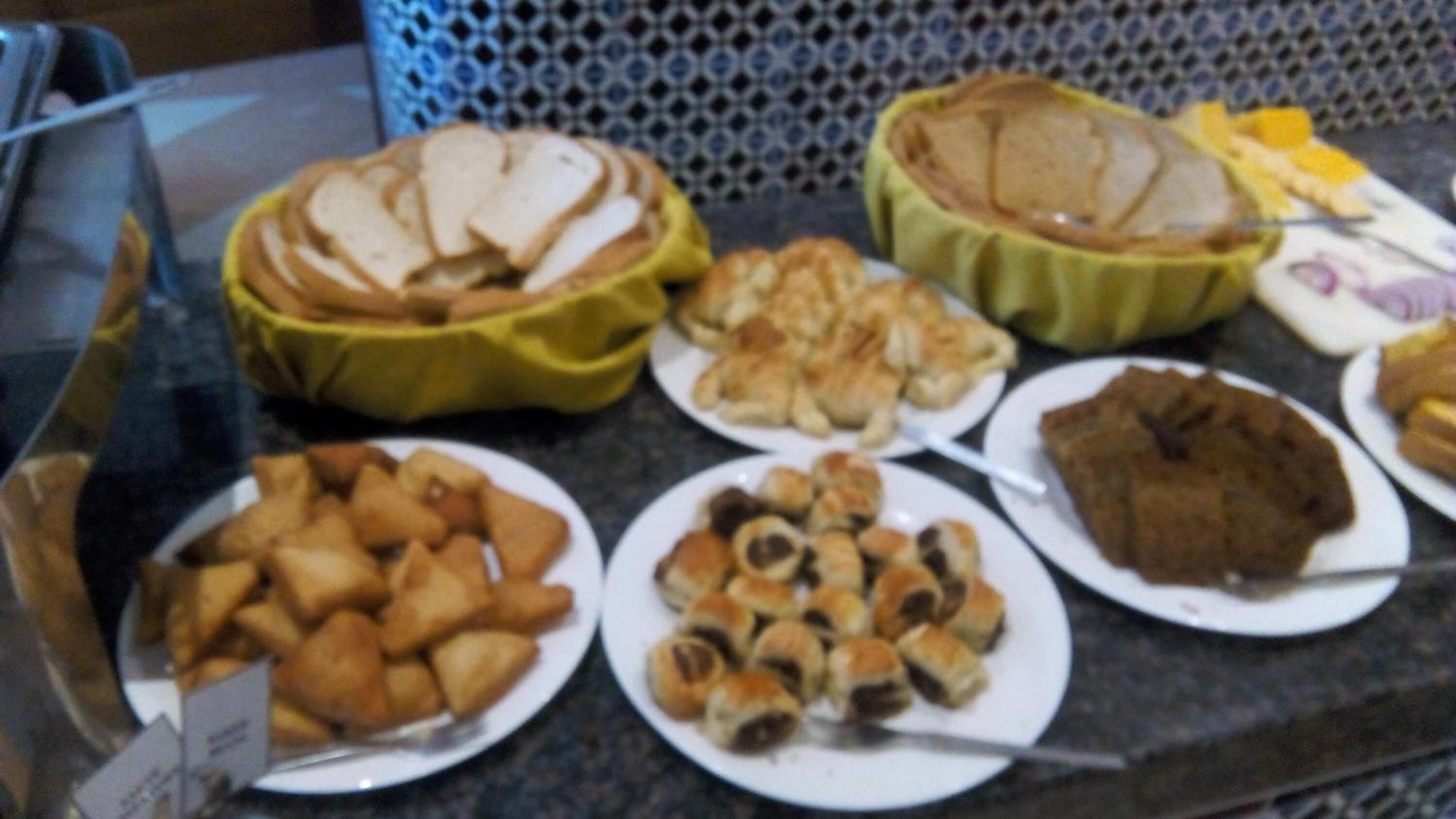 A buffet with various food items including pies, pastries, and rolls.