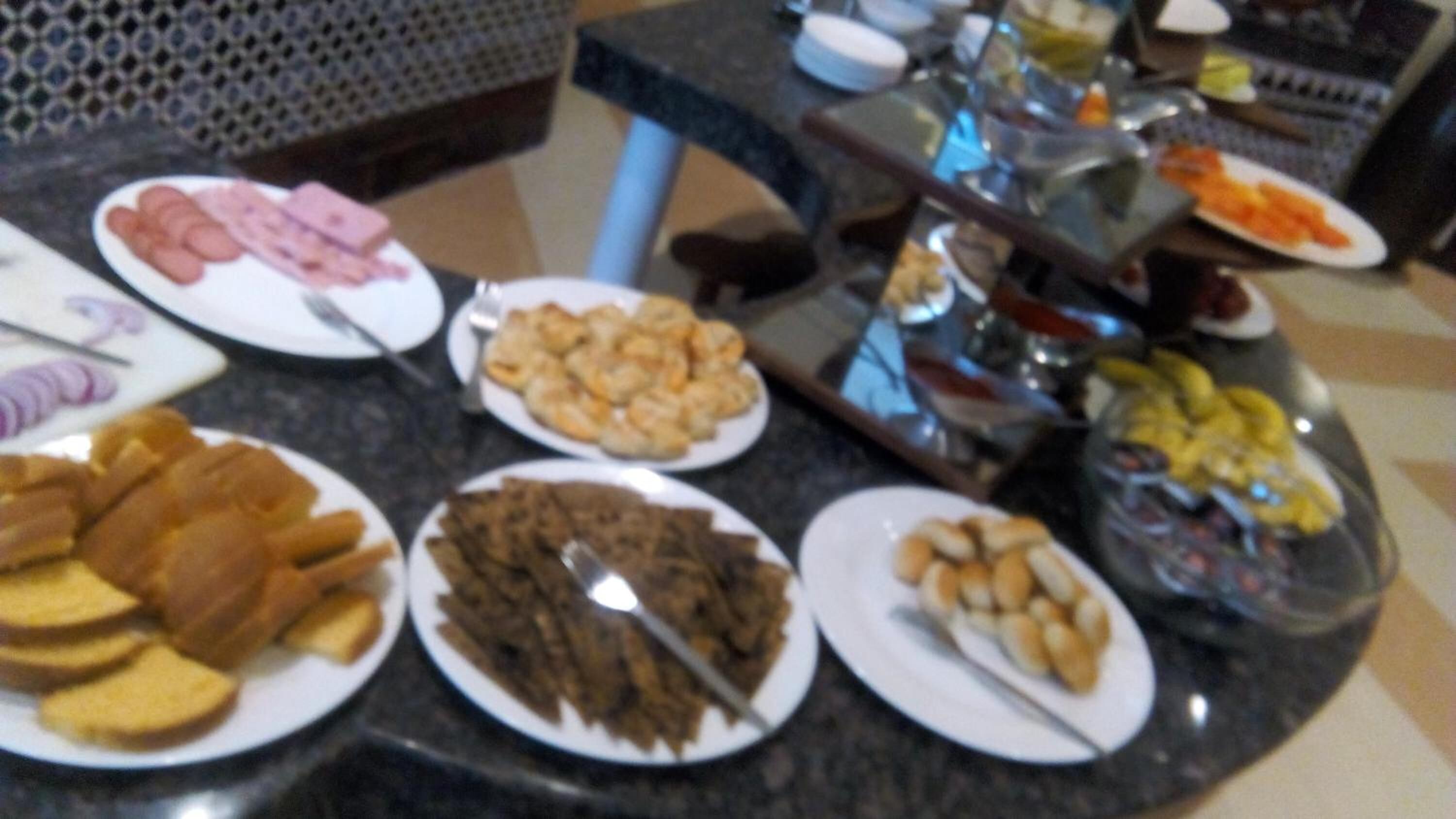 A buffet table with various food items including sliced meats, pastries, and fruits.