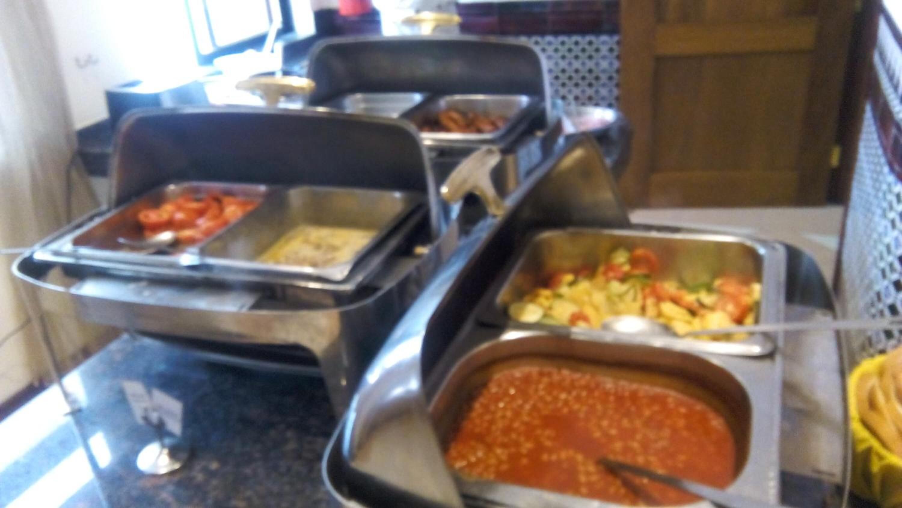 Buffet com diversos pratos, incluindo massa, legumes e molho vermelho.