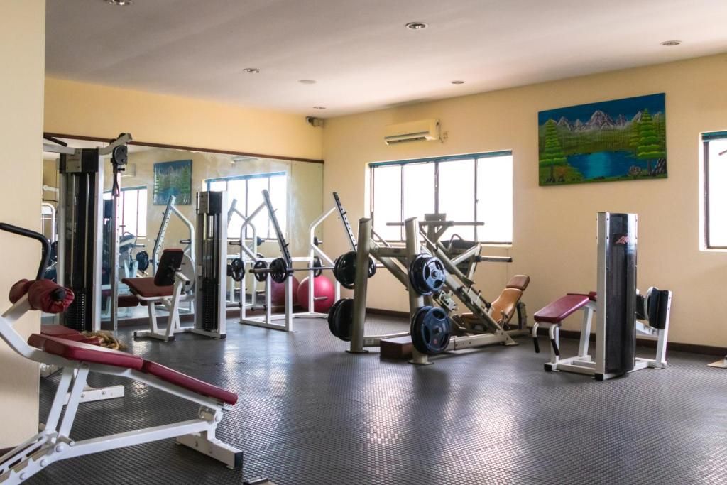 Ein Fitnessstudio mit unterschiedlichen Trainingsgeräten, großen Fenstern und einem Bild an der Wand.