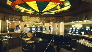 A bar area with a drum set, a jukebox, and a neon sign. - Royal Court Hotel (Mombasa)