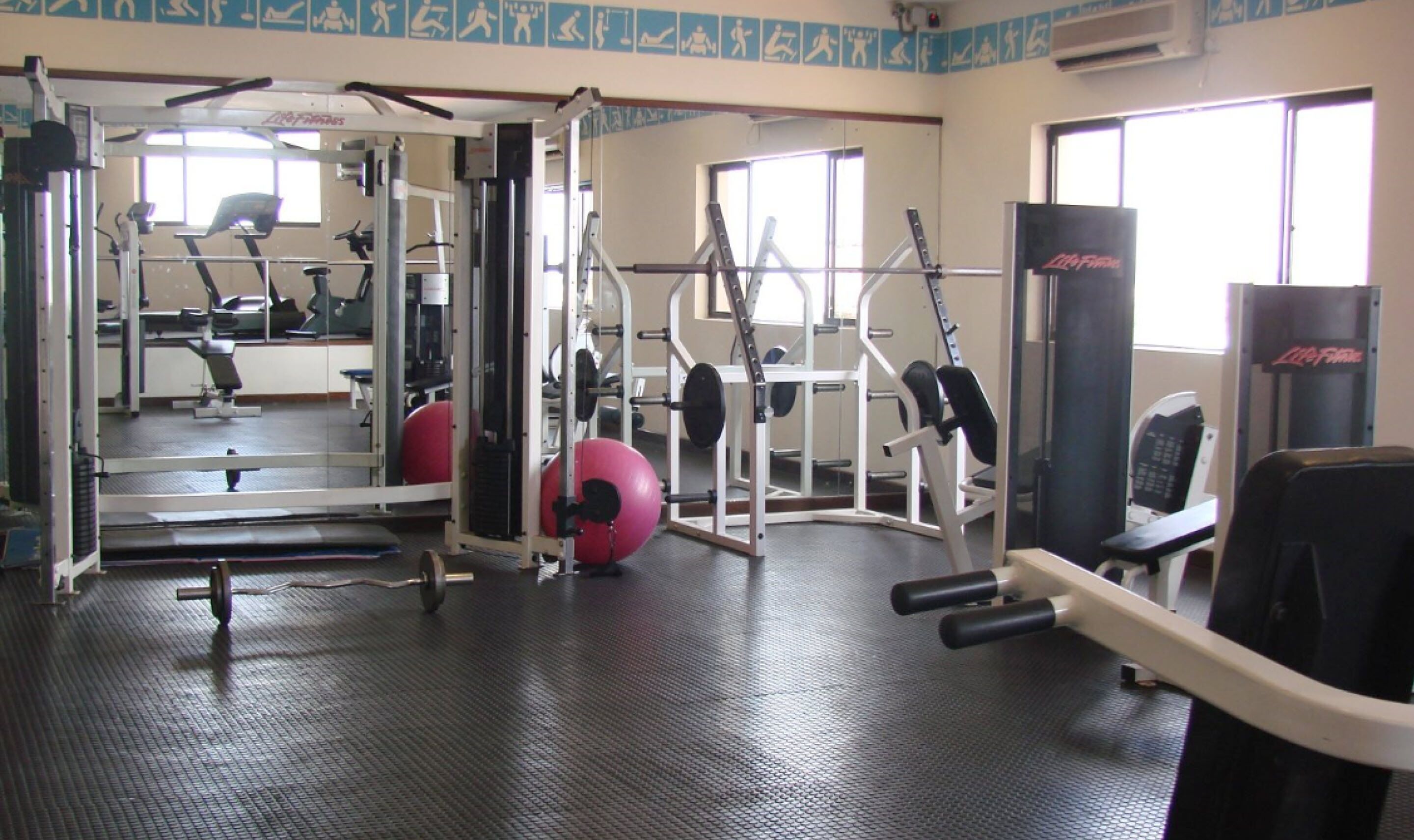 A gym with various exercise equipment, including treadmills, weight machines, and free weights.