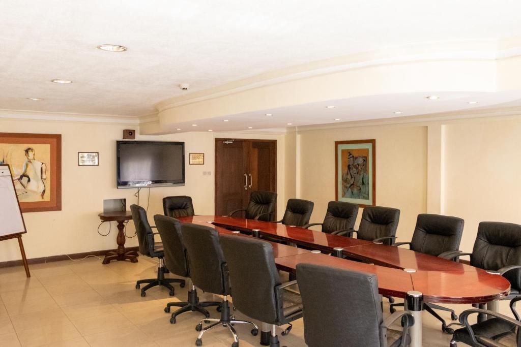A conference room with a long table, multiple chairs, a television, and framed artwork on the walls.
