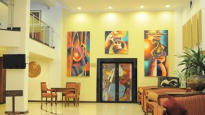 A lobby with a staircase, a reception desk, and a seating area with tables and chairs. - Royal Court Hotel (Mombasa)