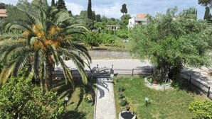 A garden with a palm tree, a stone pathway, and a circular flower bed. - Anna Apartments (Corfu)
