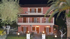 A two-story building with balconies, a gated entrance, and outdoor seating. - Anna Apartments (Corfu)