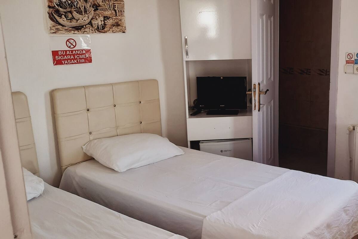 A hotel room with two beds, a television, a desk, and a chair.